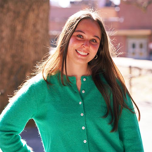 Smiling young woman in a green cardigan outdoors.